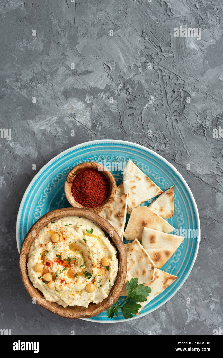 Ceci Hummus e Pita Chips su sfondo di calcestruzzo. Vista da sopra con copia spazio per il testo. Arabo, libanese, Vegana Vegetariana e dip o snack Foto Stock