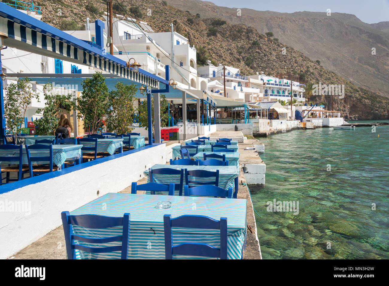Tavole di ristorante in riva al mare nella pittoresca cittadina di Loutro in Creta, Grecia Foto Stock