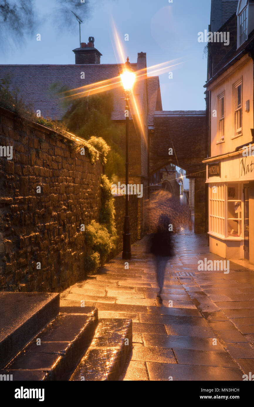 Donna sotto la pioggia in una serata estiva, Sherborne, Dorset, England, Regno Unito Foto Stock