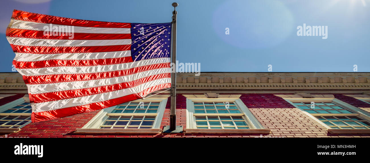 Una bandiera su un edificio di mattoni, con un paio di macchie solari, in Alexandria, Virginia. Foto Stock