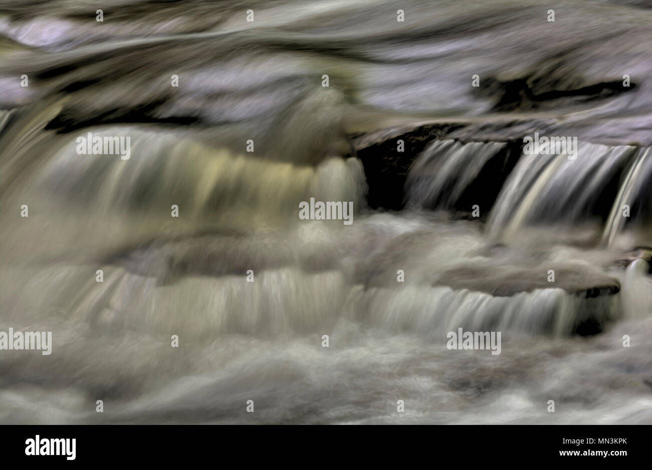 Un primo piano di una piccola cascata che mostra tutti gli intricati movimento dell'acqua che cade e volute sulle rocce in streambed. Elaborati come un Foto Stock