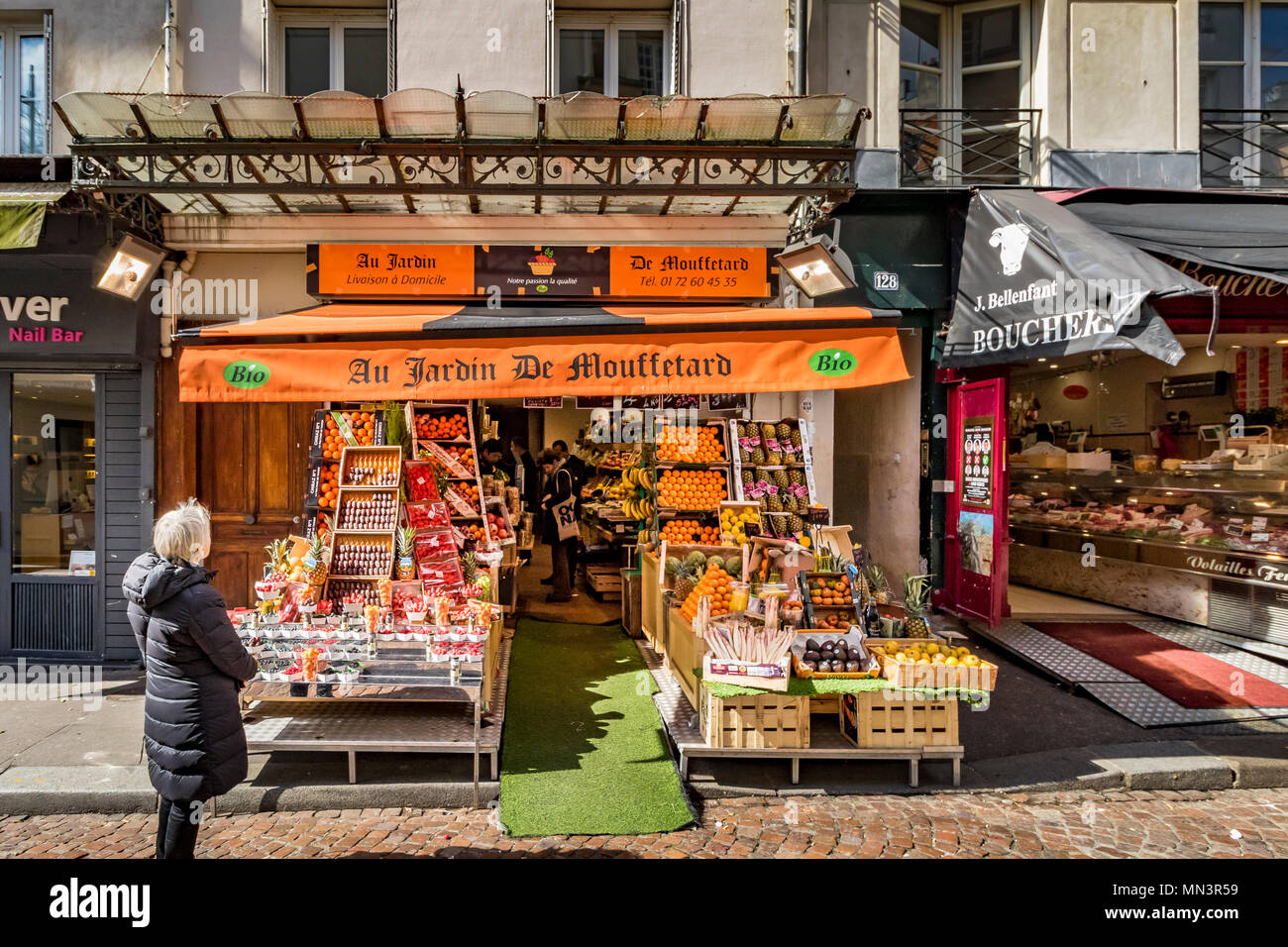 Una donna che guarda all'Au Jardin De Mouffetard ,a frutta e verdura shop on Rue Mouffetard, Parigi, Francia Foto Stock