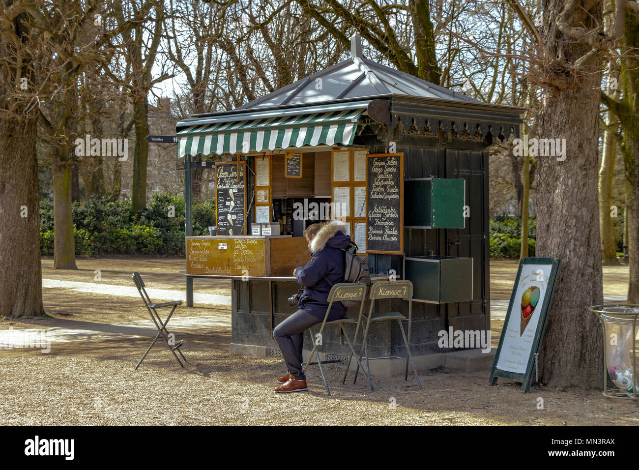 Un uomo seduto al di fuori del chiosco n. 7 al Jardin du Luxembourg che vende una vasta gamma di bevande calde e fredde e di prodotti alimentari , paris , France Foto Stock