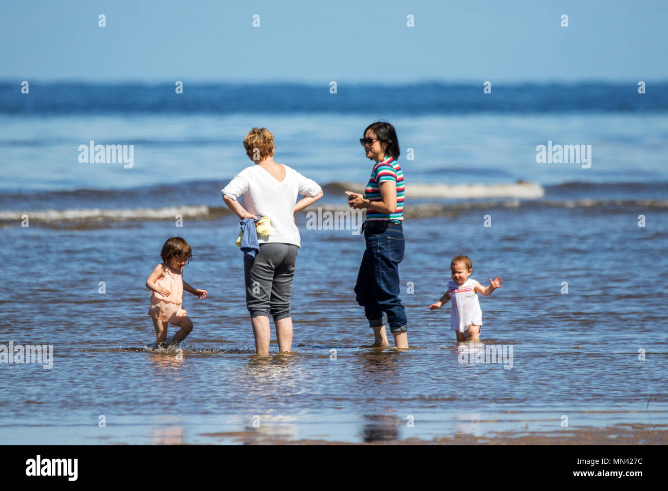 Il sole a Southport, Merseyside. 14 maggio 2018. Regno Unito Meteo. Uno splendido stile mediterraneo previsioni sulla costa nord ovest dell'Inghilterra con temperature calde, il cielo limpido e spiagge di sabbia dorata e come due piccoli bambini mostrano la mamma come è fatta come essi wade in acque poco profonde lungo il litorale della marea sulla spiaggia di Southport nel Merseyside. Credito: Cernan Elias/Alamy Live News Foto Stock