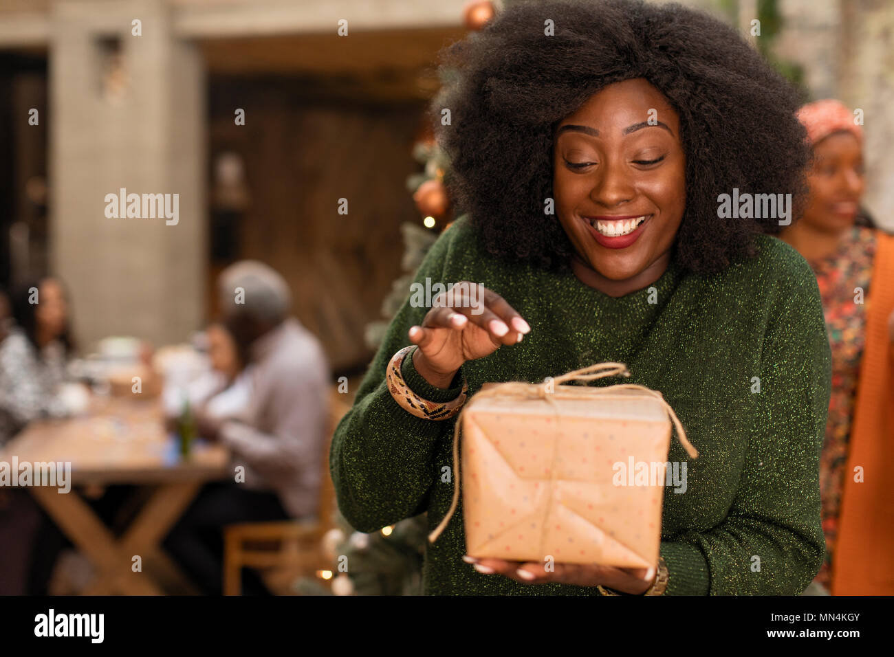 Curioso, entusiasta giovane donna apertura regalo di Natale Foto Stock