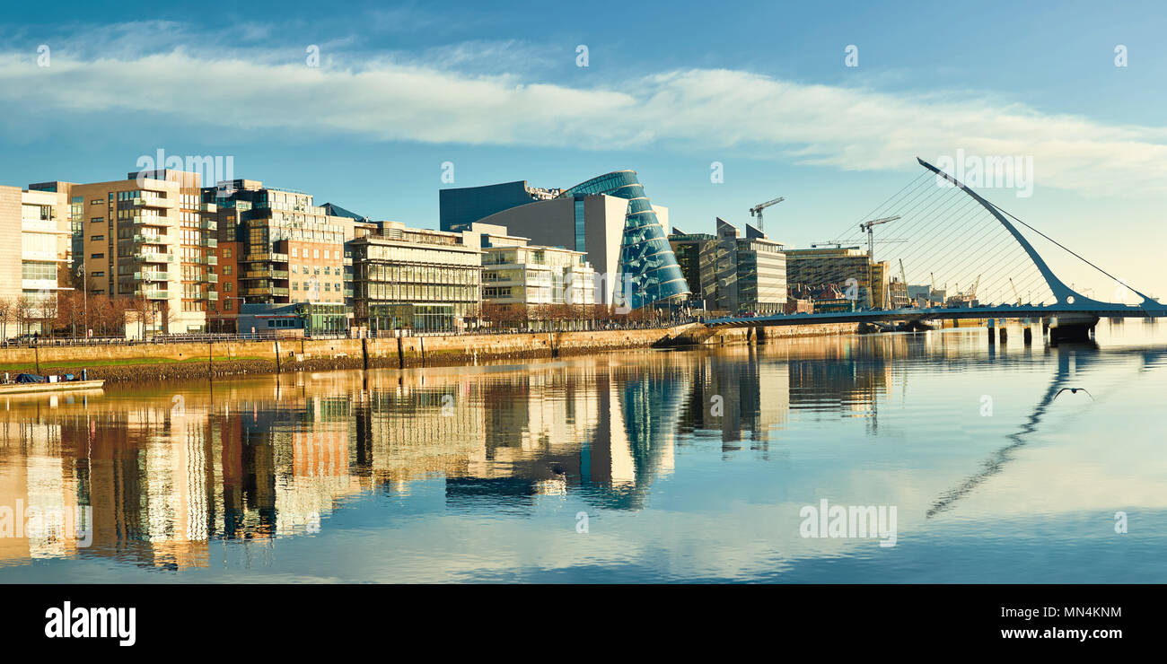 Edifici moderni e uffici sul fiume Liffey a Dublino su una luminosa giornata di sole, con l'Arpa ponte sulla destra Foto Stock