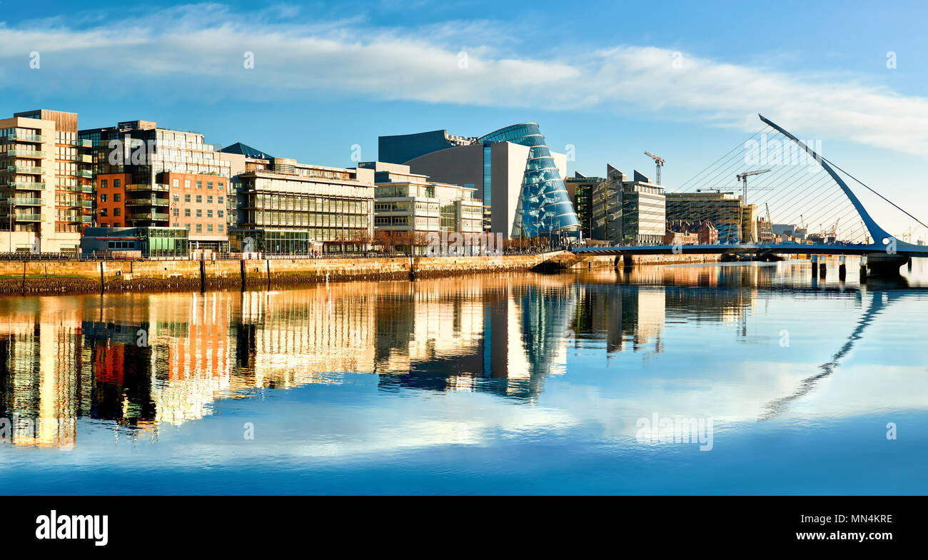 Edifici moderni e uffici sul fiume Liffey a Dublino su una luminosa giornata di sole, con l'Arpa ponte sulla destra Foto Stock