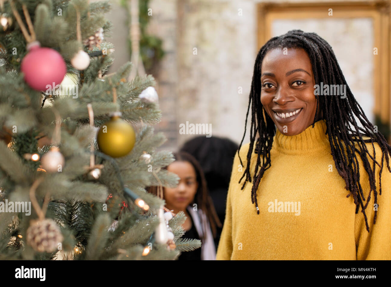 Ritratto sorridente, fiducioso donna ad albero di Natale Foto Stock