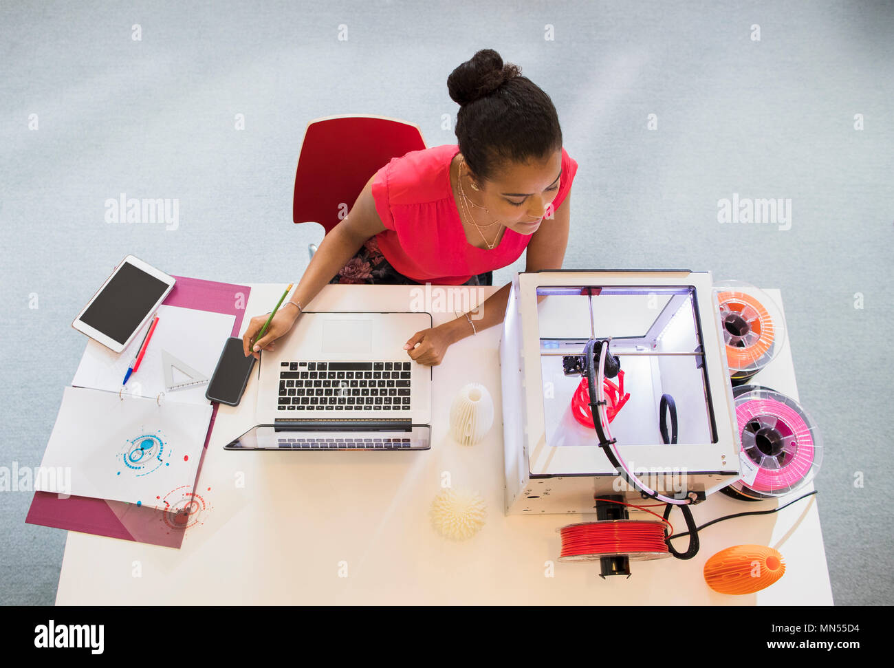 Designer femmina al computer portatile guarda la stampante 3D Foto Stock