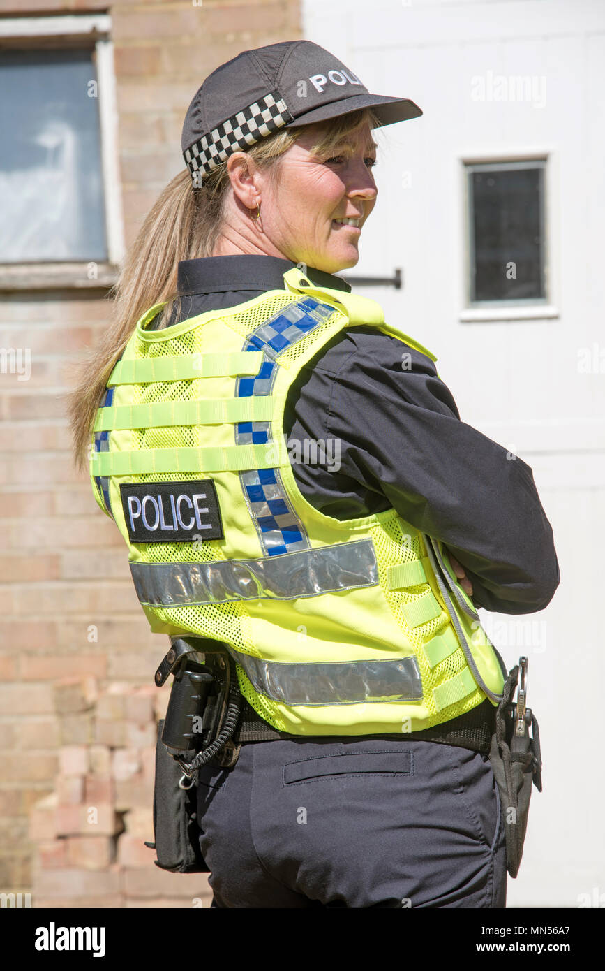 Parte posteriore e laterale verticale di una donna poliziotto che indossa un cappello Foto Stock