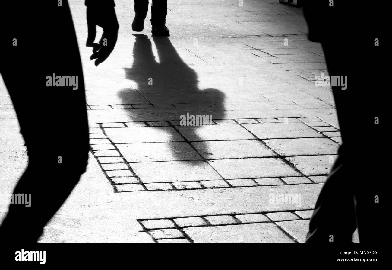 Ombra silhouette di due persone sul marciapiede della città in bianco e nero Foto Stock