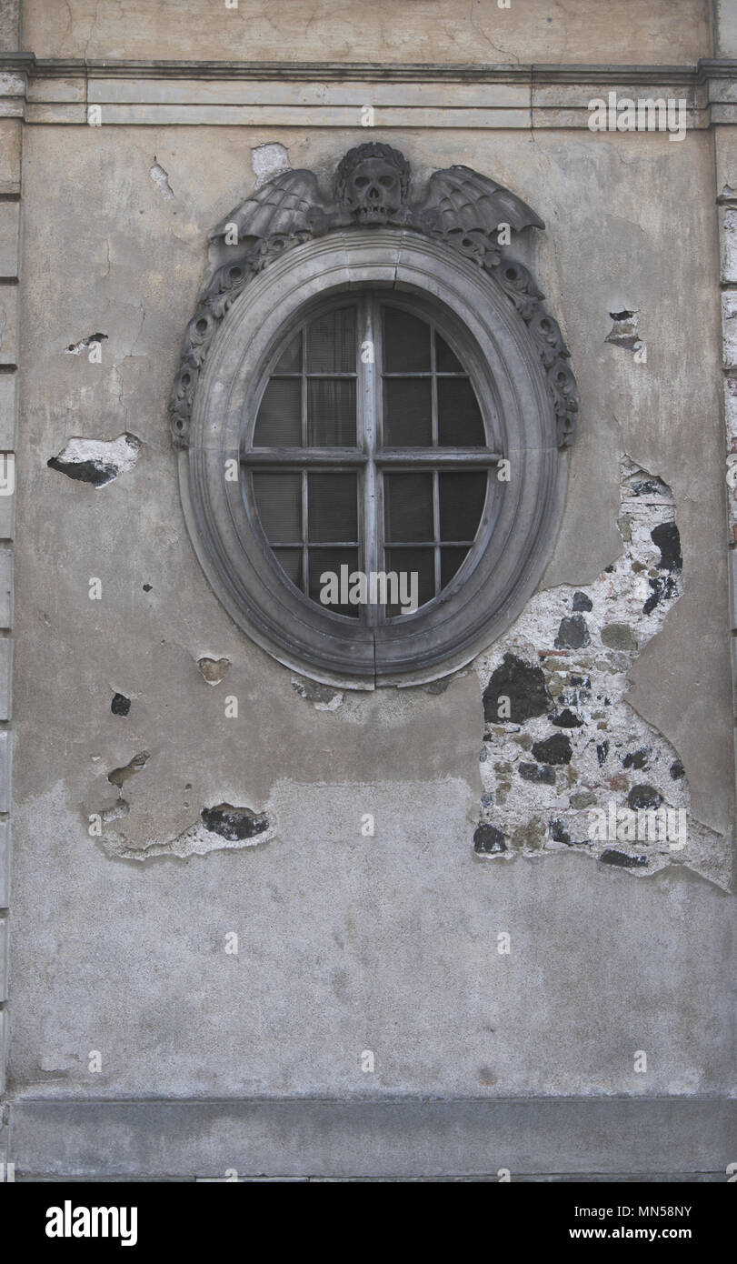 Finestra rotonda della chiesa morgue con cranio e alette sulla parte superiore. Colpo verticale. Foto Stock