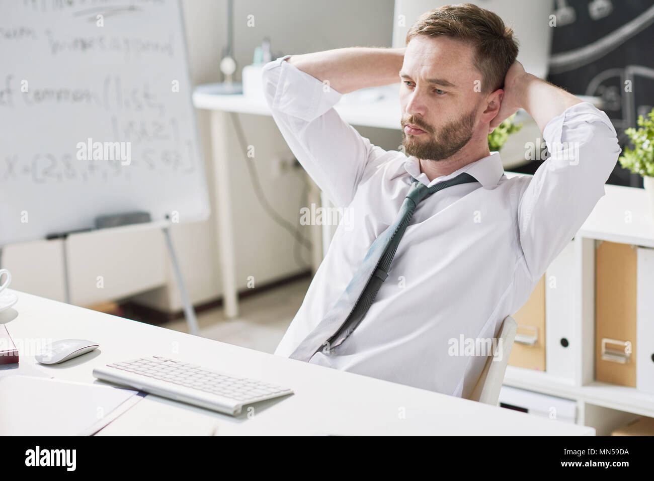 Ritratto di bello barbuto imprenditore rilassarsi seduti alla scrivania in ufficio e pensare mentre utilizzando i moderni computer sul posto di lavoro, lo spazio di copia Foto Stock