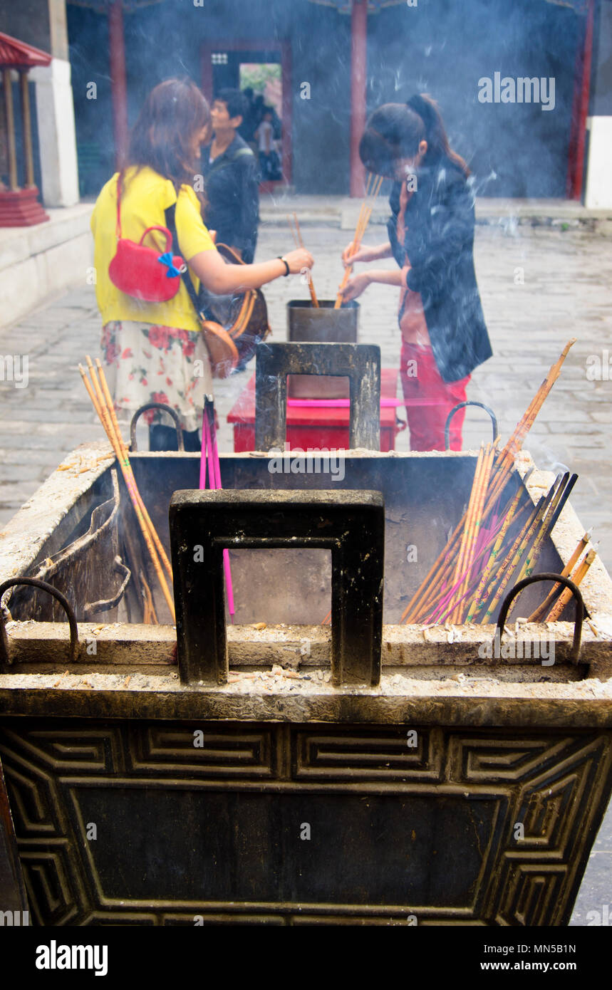 Le donne cinesi di illuminazione bastoncini di incenso presso il centro storico di Tempio di Yonghegong a Pechino in Cina, apparentemente inghiottito nel fumo da un adiacente incenso s Foto Stock