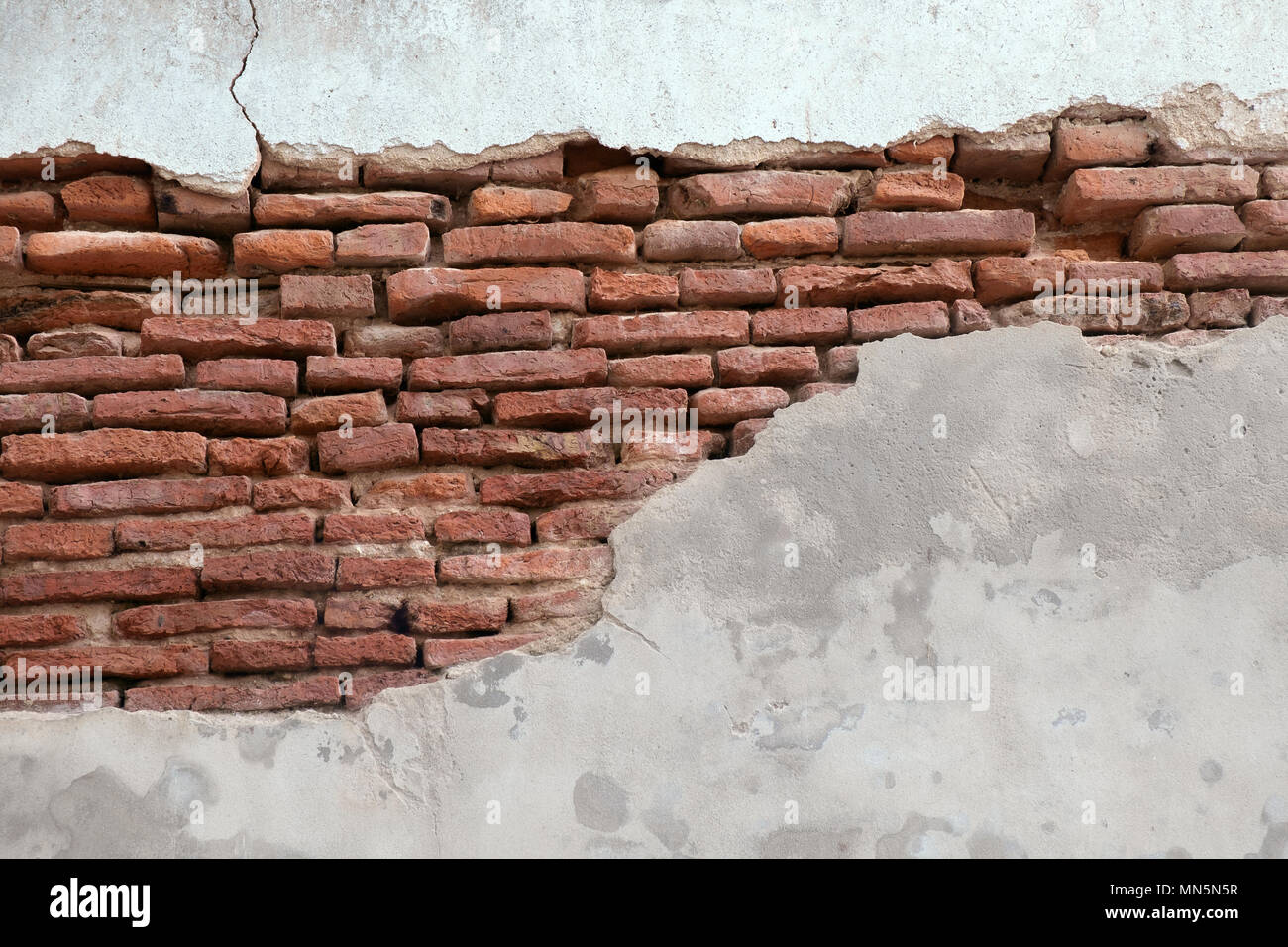 Sullo sfondo di un vecchio muro di mattoni rotti. Foto Stock