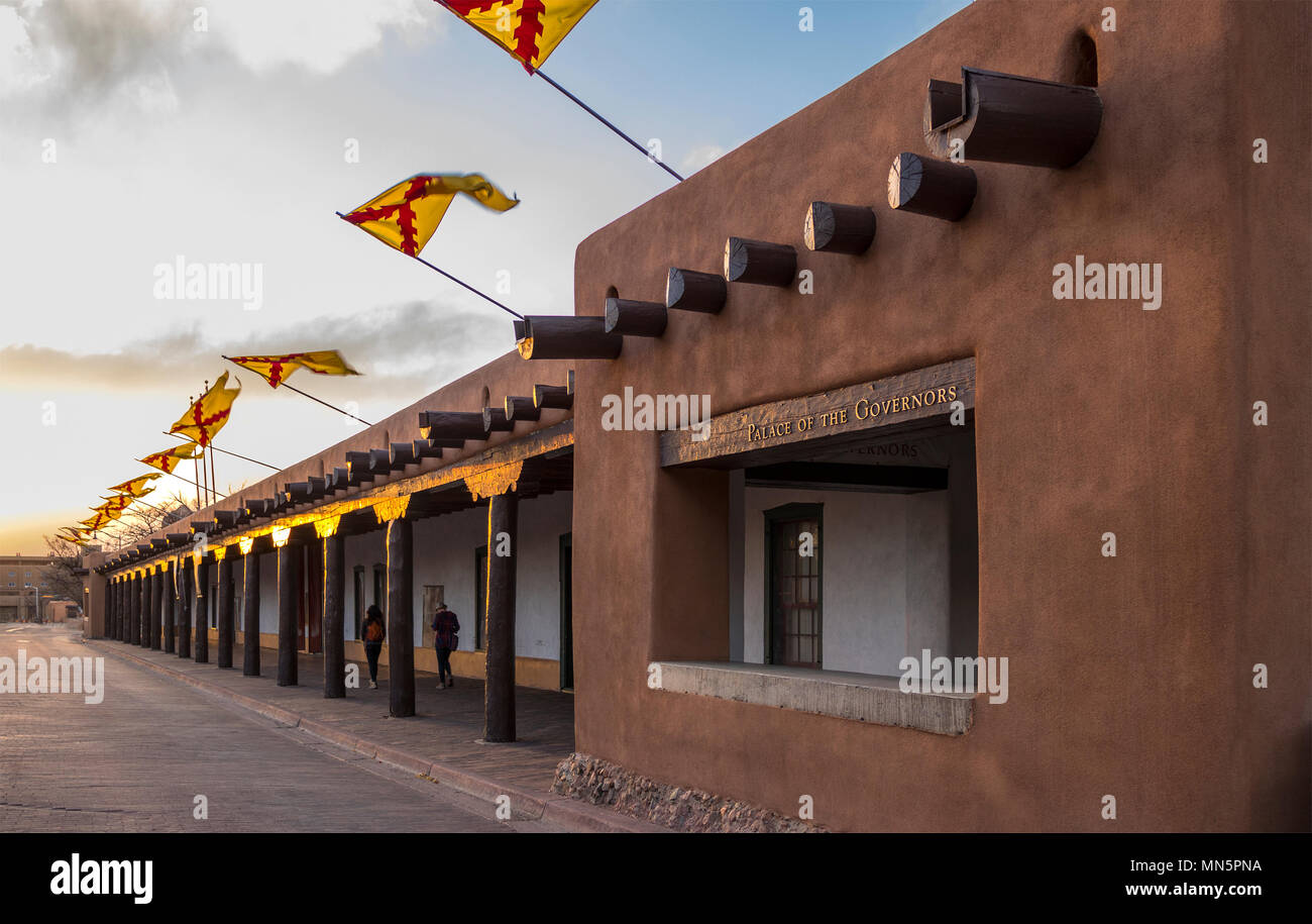 Bandiere sopra il Palazzo dei Governatori, Santa Fe Plaza, capitale dello Stato, Nuovo Messico al tramonto di una sera primaverile. Storica struttura di adobe. Foto Stock