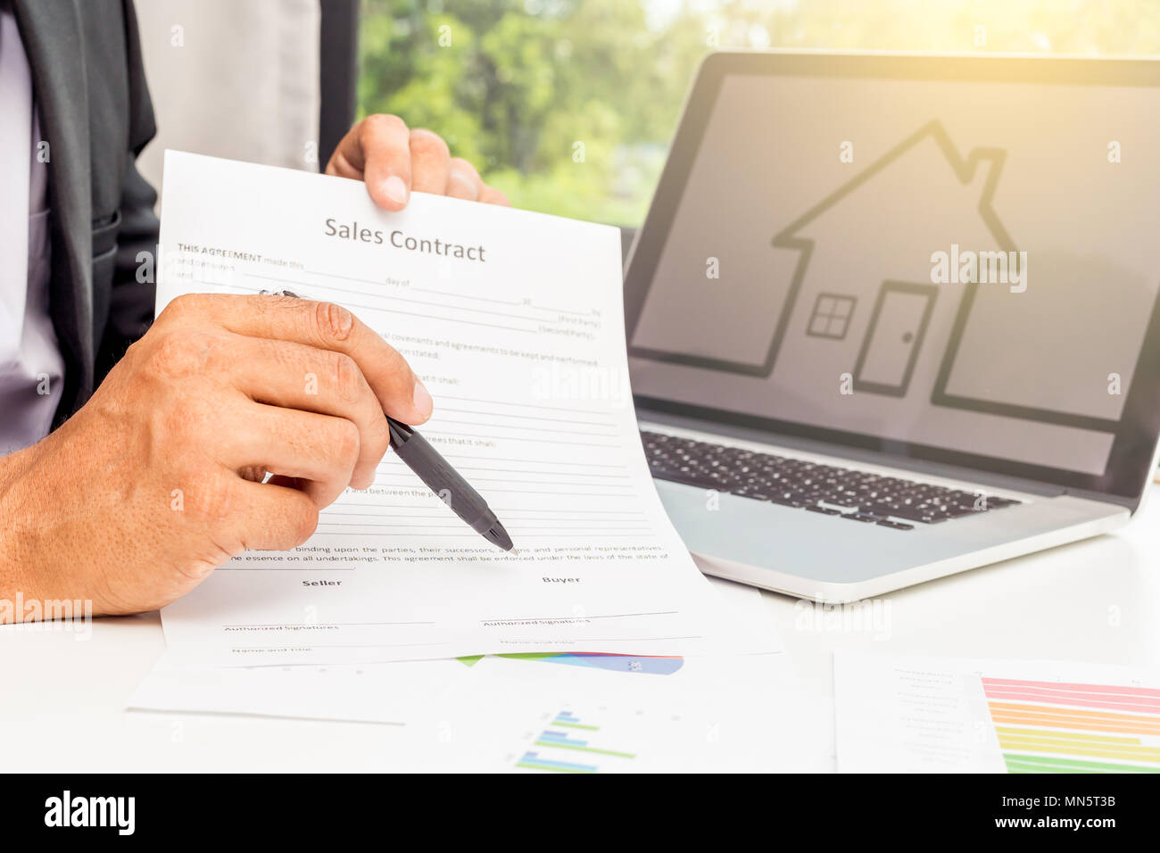 Azienda giovane agente ha mostrato il contratto di vendita e lo si punta verso la scrivania in ufficio Foto Stock