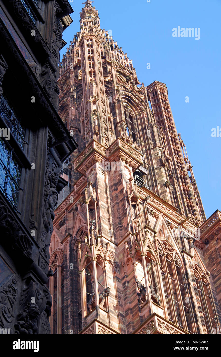 La torre e la guglia sul fronte ovest della cattedrale di Notre Dame de Strasbourg, con angolo di medievale adiacente edificio con travi di legno. Foto Stock