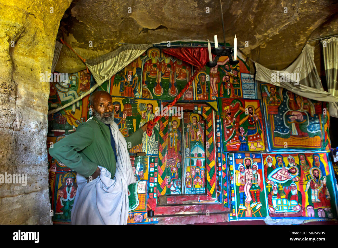 Sacerdote mostra dipinti su tela con motivi biblici in interieur del rock-conci di chiesa Mikael Mellehayzengi, Tsaeda Amba, Tigray, Etiopia Foto Stock