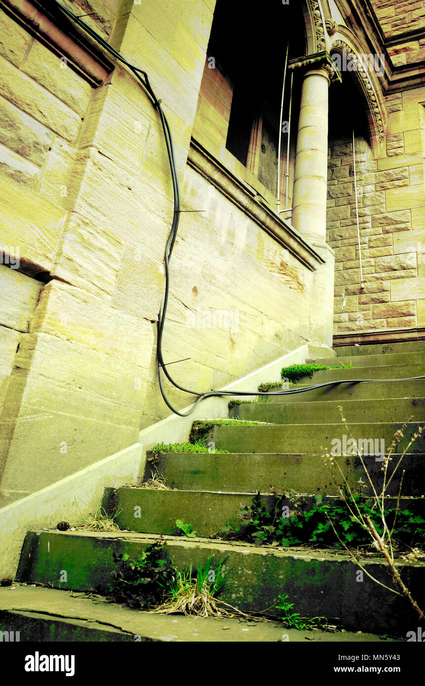 Un palazzo abbandonati con grande scalinata verso una porta laterale Foto Stock
