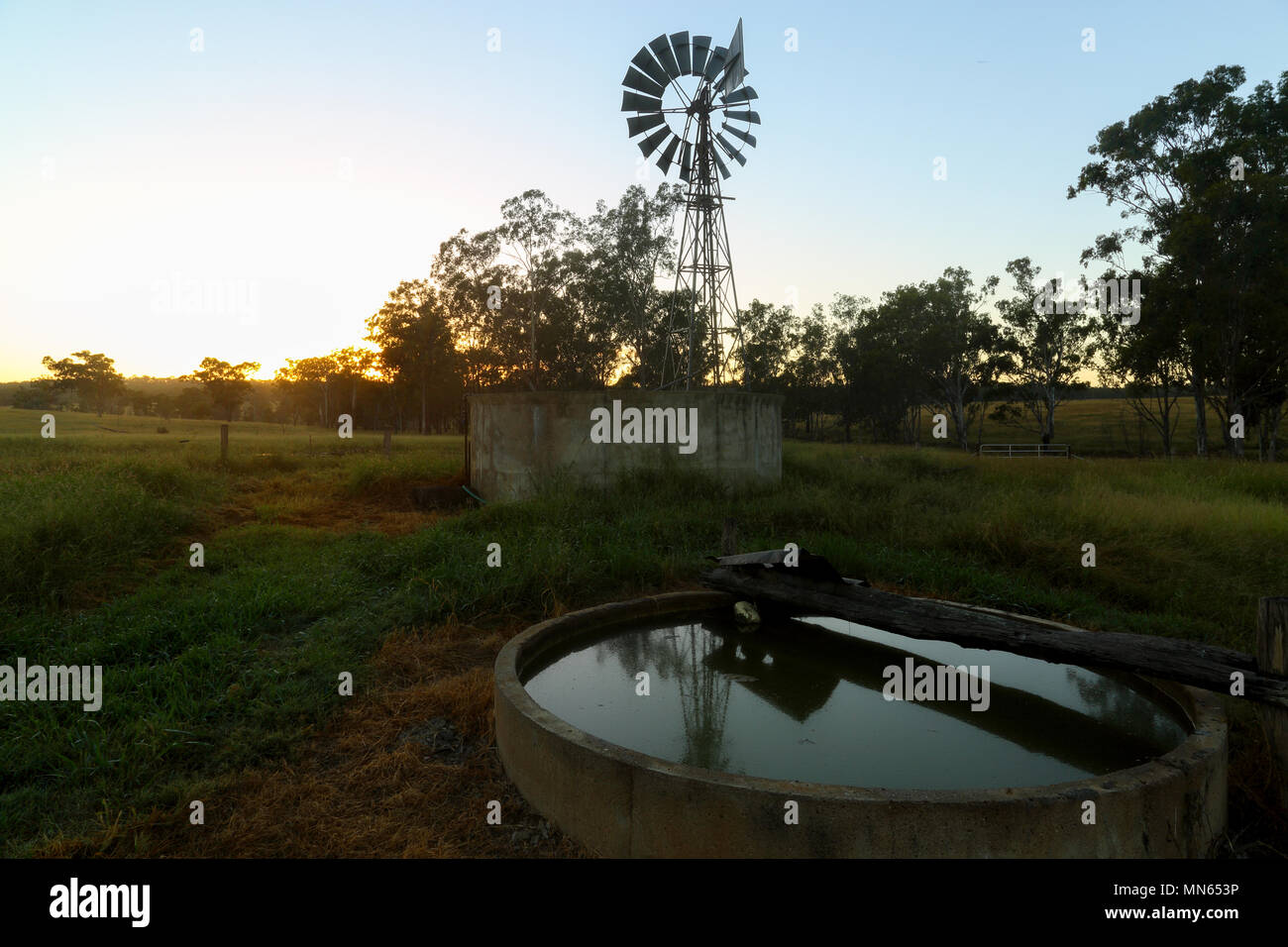 Tramonto su un wingmill e serbatoio di acqua in una fattoria nel Queensland, in Australia. Foto Stock