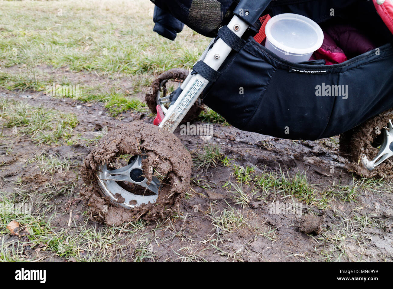 Passeggino ruote incrostato di fango su fondi fangosi a piedi nel quartiere di picco nella molla variabile meteo Foto Stock