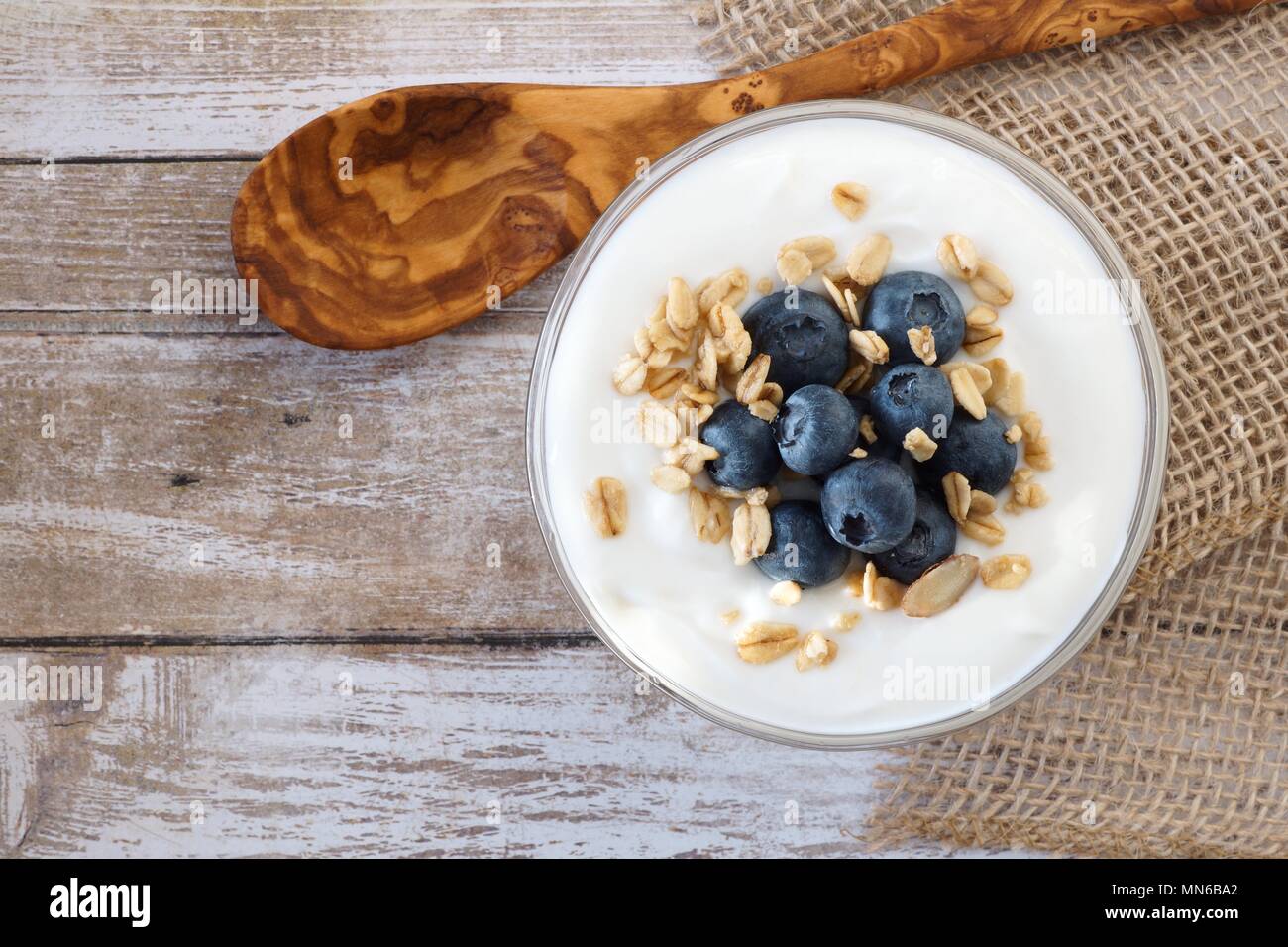 Yogurt con mirtilli dolci e granola, sopra visualizza su legno rustico Foto Stock