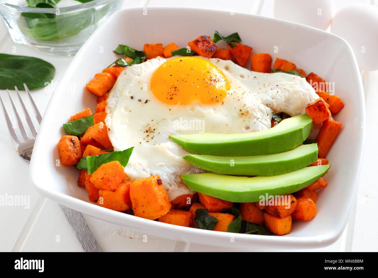 La colazione nutriente ciotola con patate dolci, uova, avocado e spinaci, vicino la scena della tabella Foto Stock