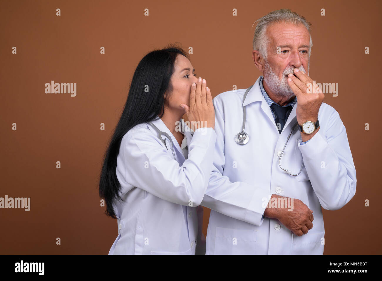 Coppia multi-etnico giovane medici contro lo sfondo marrone Foto Stock