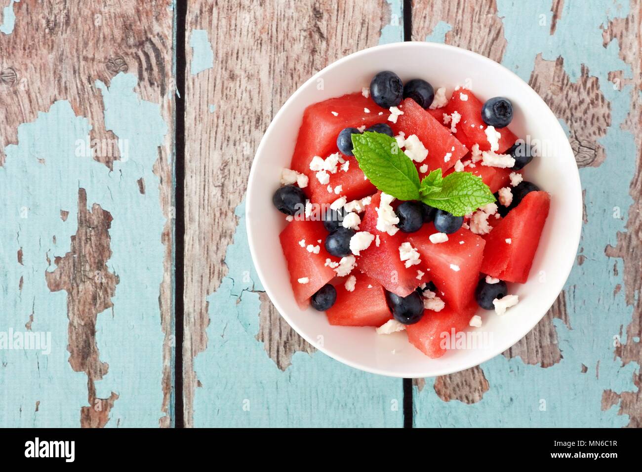 Insalata estiva con cocomero, mirtilli e il formaggio feta, sopra visualizza su un rustico blu sullo sfondo di legno Foto Stock