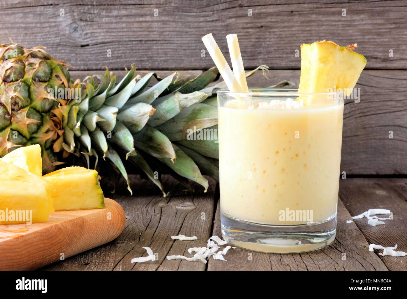 Un sano frullato di ananas in vetro, scena contro uno sfondo di legno vecchio Foto Stock