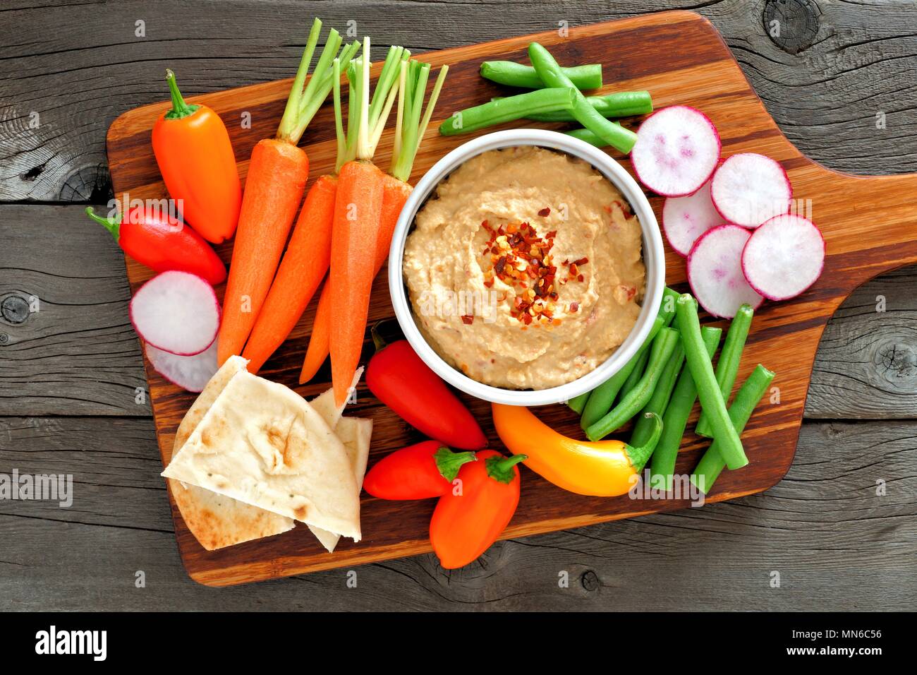 Hummus dip con un piatto di portata di verdure fresche, sopra visualizza su un sfondo di legno Foto Stock