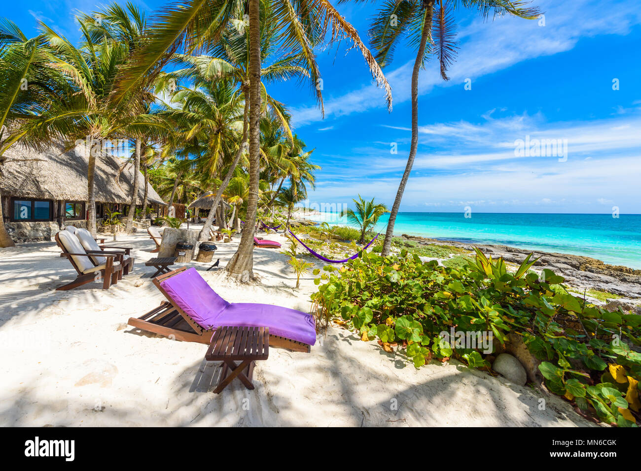 Sedie e amaca sotto le palme sulla spiaggia paradiso al resort tropicale. Riviera Maya - Caraibi costa a Tulum in Quintana Roo, Messico Foto Stock