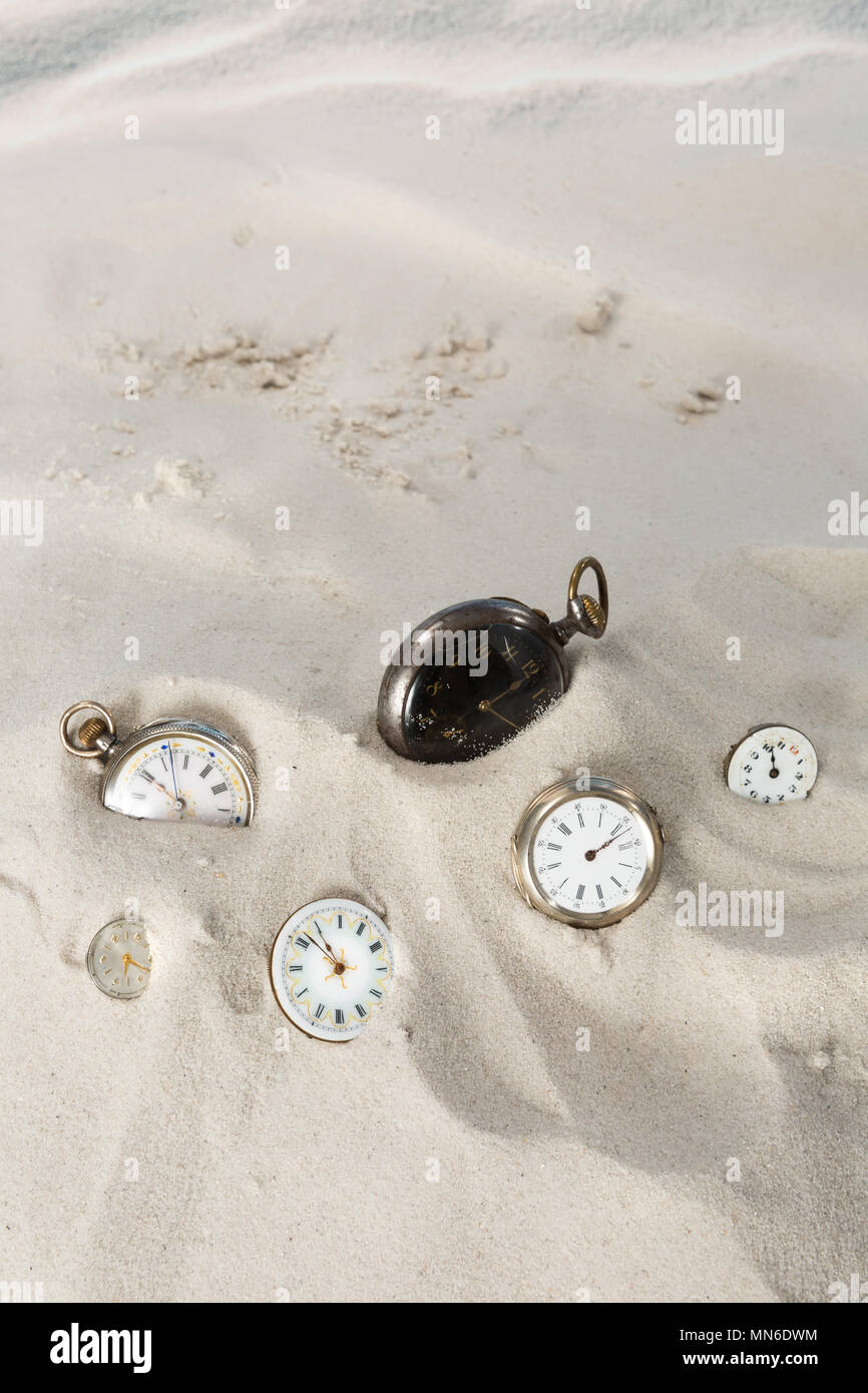 Molti antichi orologi da tasca e orologi giacente in spiaggia di sabbia Foto Stock