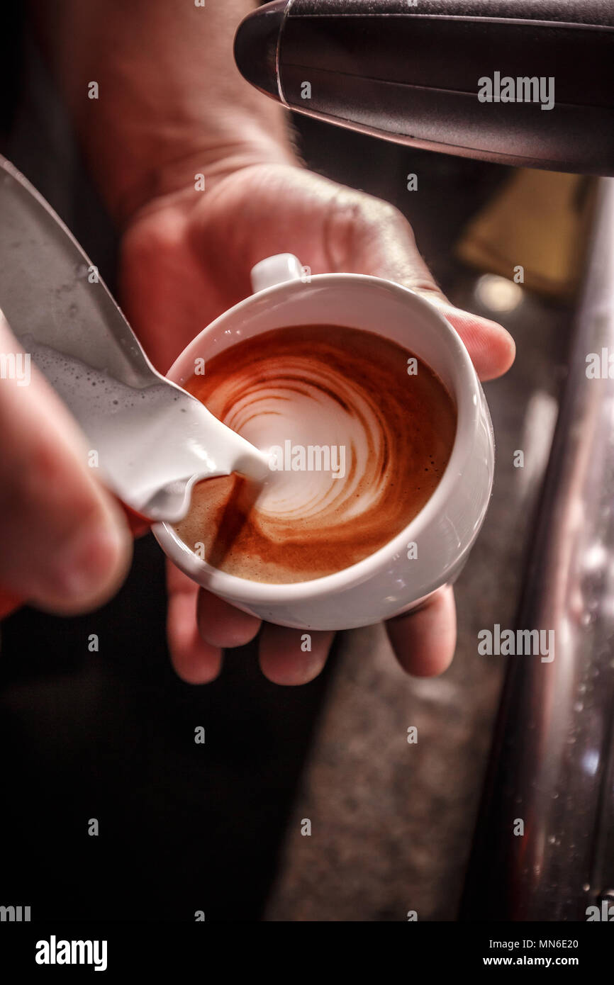 Barista fa caffè latte art, egli è versando il latte Foto Stock