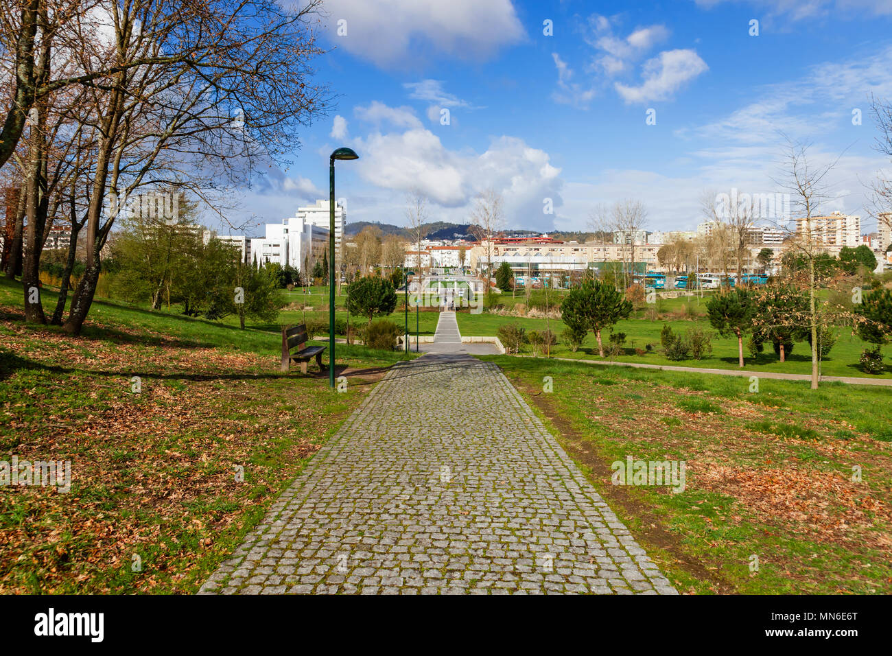 Svuotare il percorso in ciottoli, via, sentiero o percorso attraverso gli alberi e il verde prato in Parque da Devesa parco urbano. Città di Vila Nova de Famalicao, Foto Stock