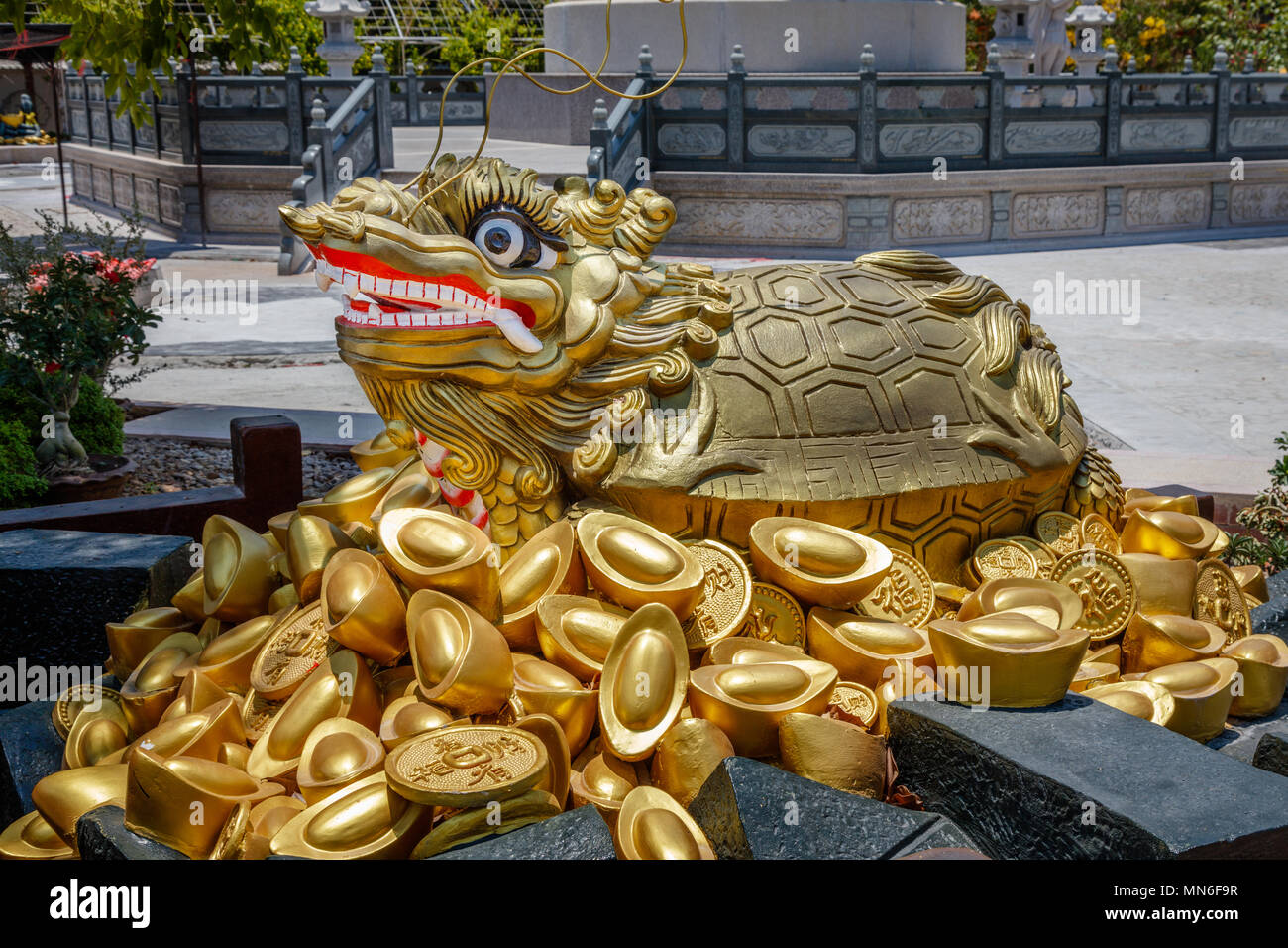 Statua di un drago tartaruga su permanente delle monete in oro e lingotti al Cinese-stile tempio Buddista Kuang Im cappella vicino al Fiume Kwai, Kanchanaburi, Thailandia. Foto Stock