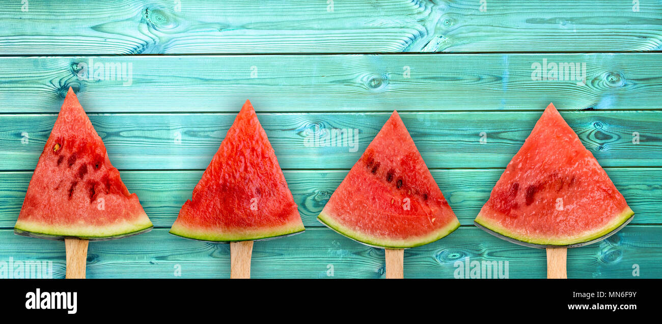 4 fetta di anguria popsicles sulla panoramica di legno blu sfondo, Frutta estiva fresca concept Foto Stock