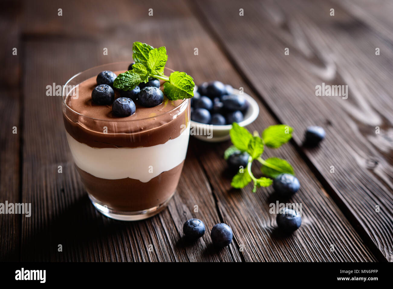 Layered cioccolato e vaniglia dessert mascarpone guarnita con mirtillo, servita in un vasetto di vetro Foto Stock