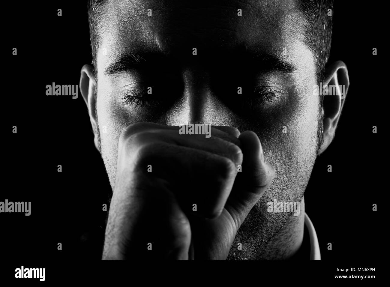 Ritratto di un uomo con pugno e gli occhi chiusi su sfondo nero Foto Stock