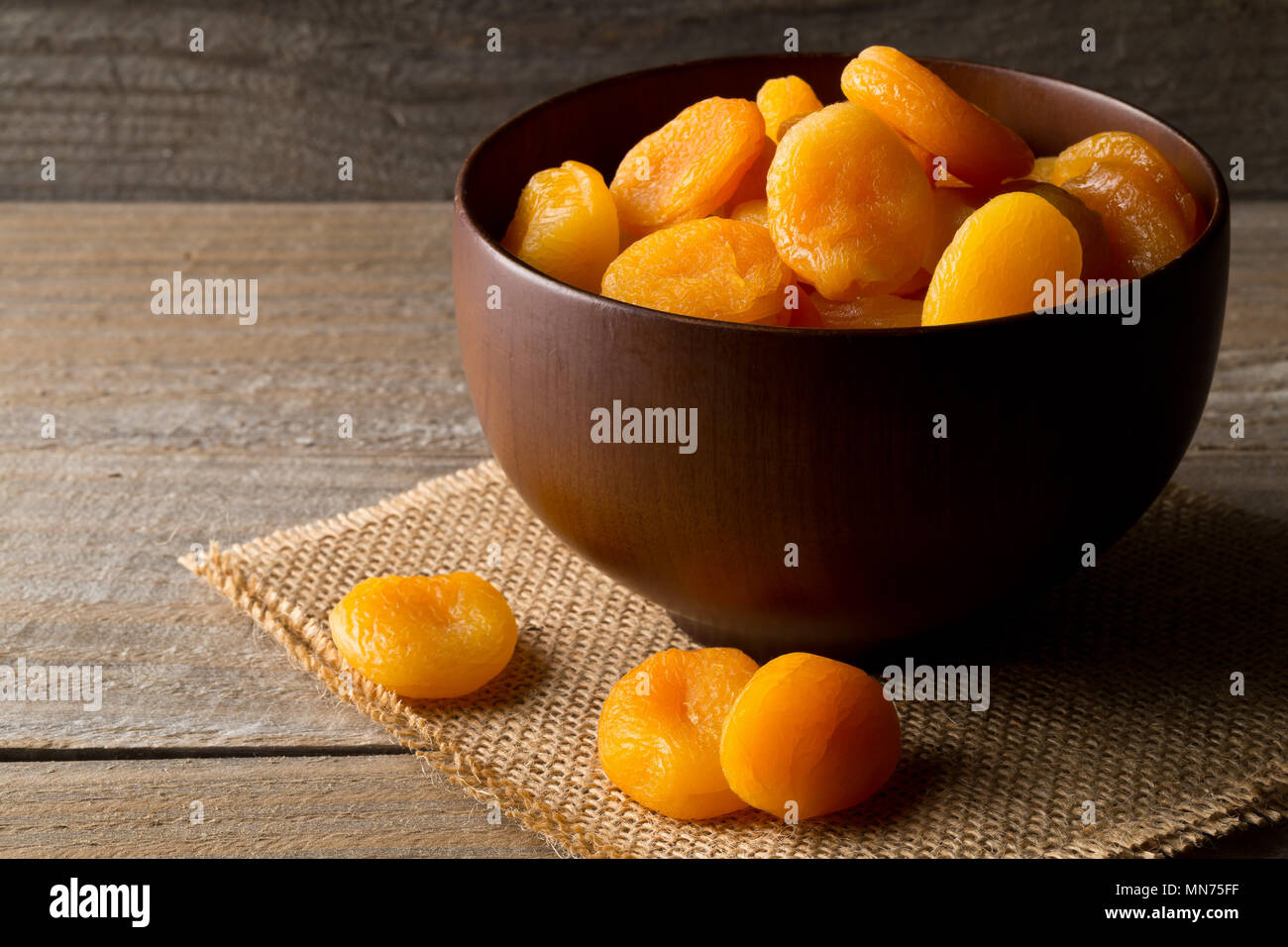 Albicocche essiccate intere frutto nella ciotola di legno sul tavolo di legno sfondo Foto Stock