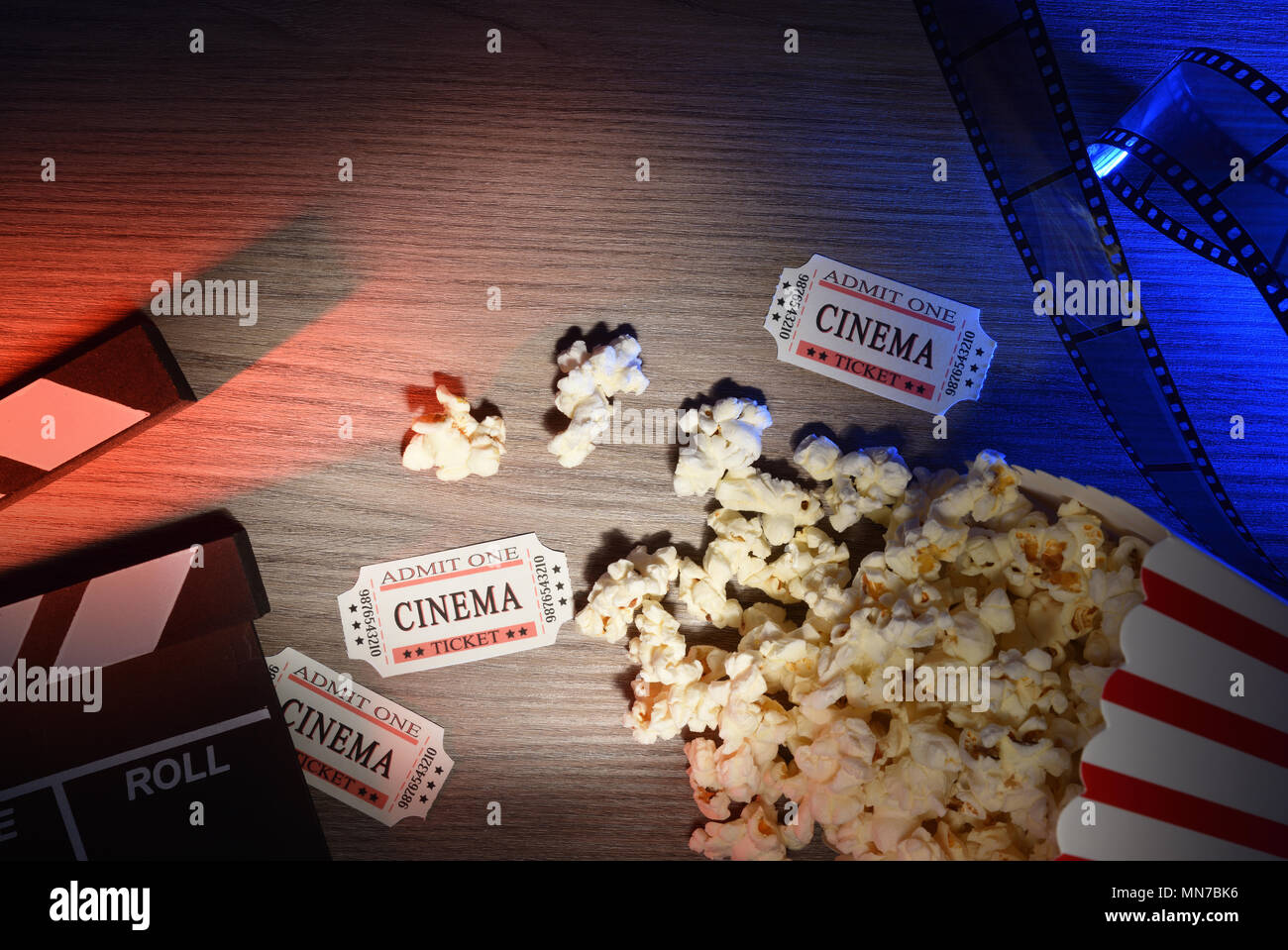 Le attrezzature e gli elementi del cinema sul tavolo di legno con luci colorate. Concetto di guardare film. Composizione orizzontale. Vista dall'alto. Foto Stock