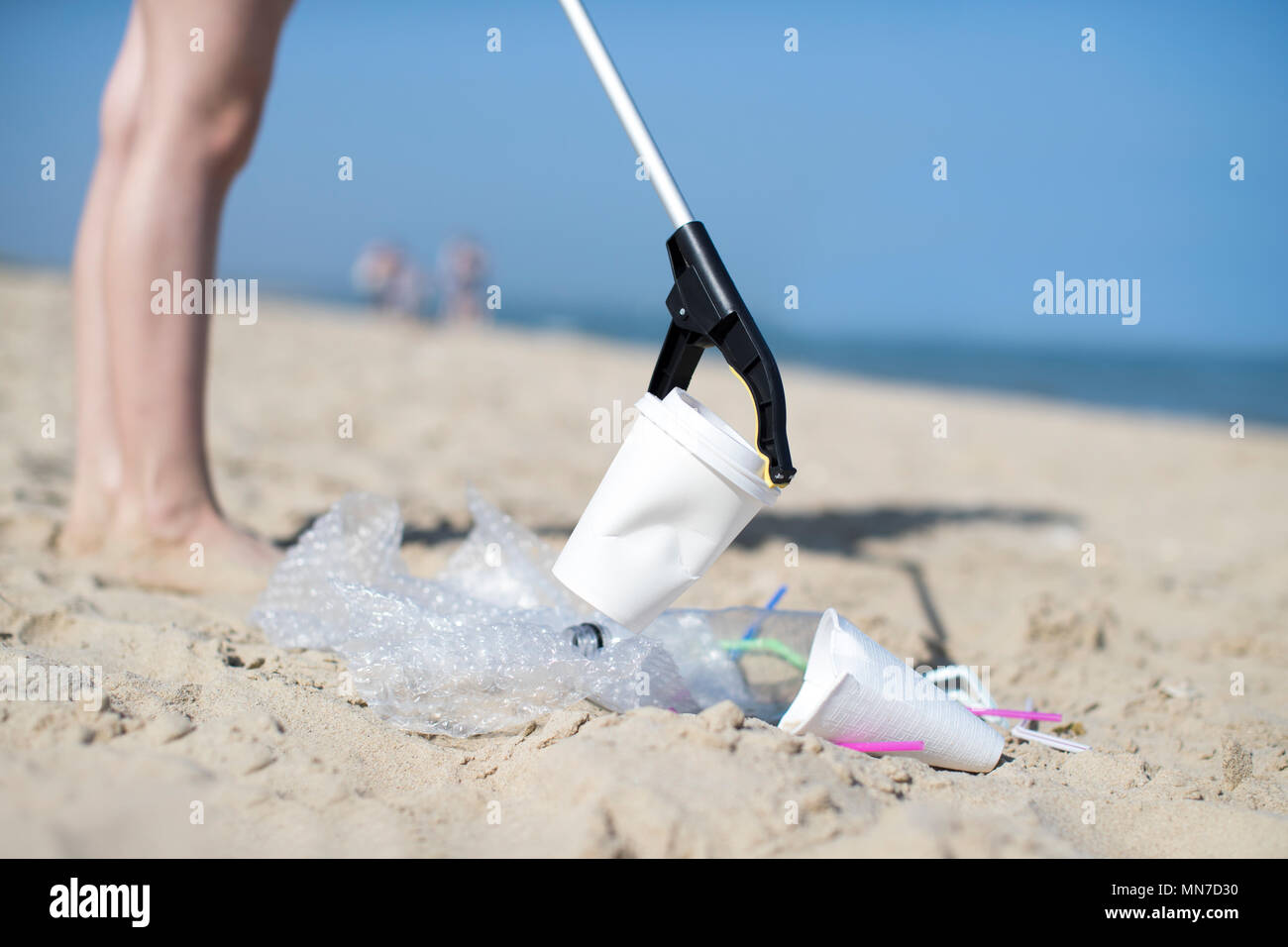 Close Up di persona la raccolta dei rifiuti di plastica da spiaggia inquinata mediante raccoglitrice di lettiera Foto Stock