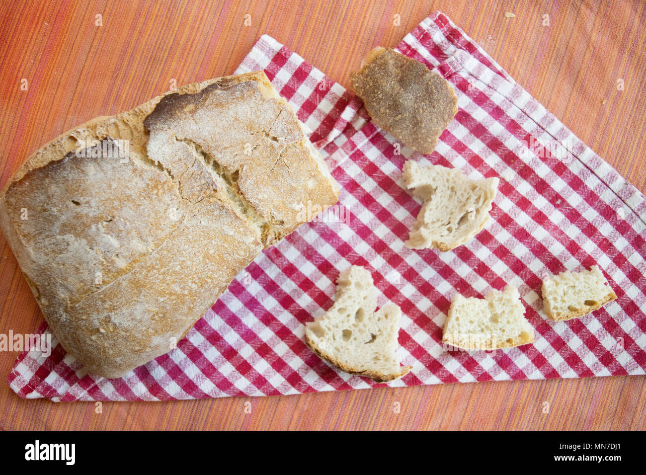 Filone di pane francese con vicino alcuni piccoli pezzi di esso Foto Stock