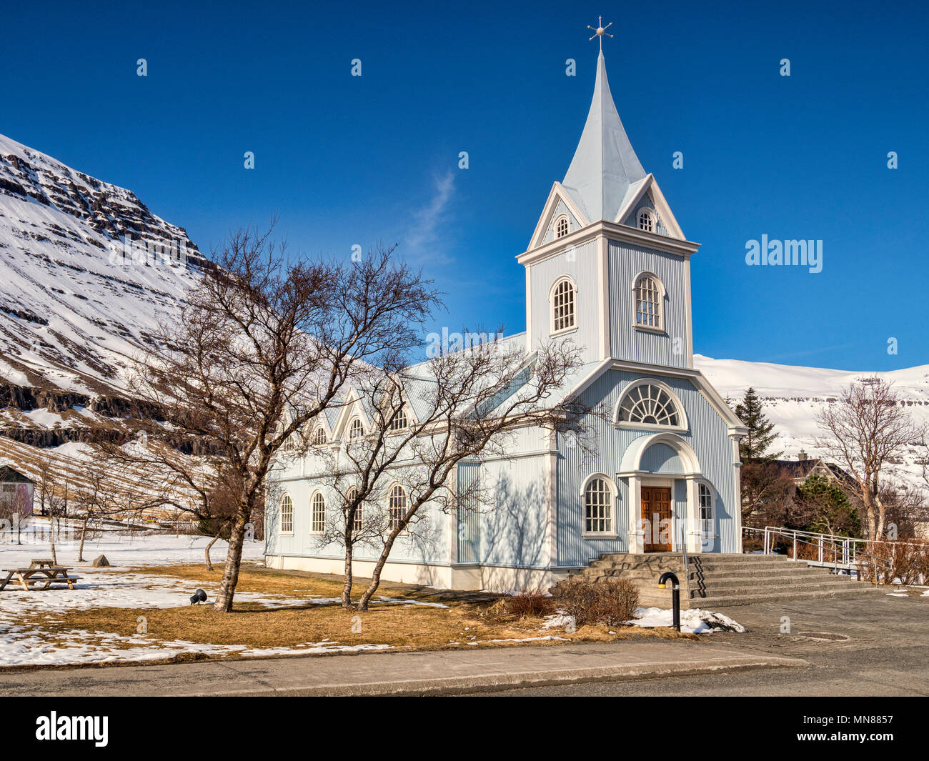 La famosa chiesa blu a Seyðisfjörður Affitto, Est Islanda, su una luminosa giornata di primavera con montagne innevate. Foto Stock