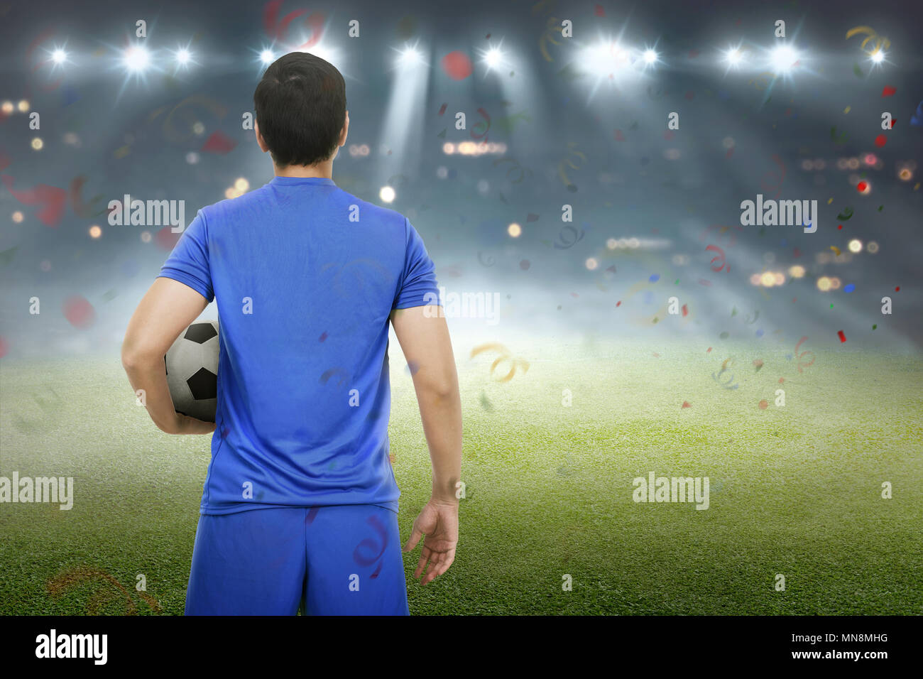 Vista posteriore di asian giocatore di football in piedi con la palla sul campo Foto Stock