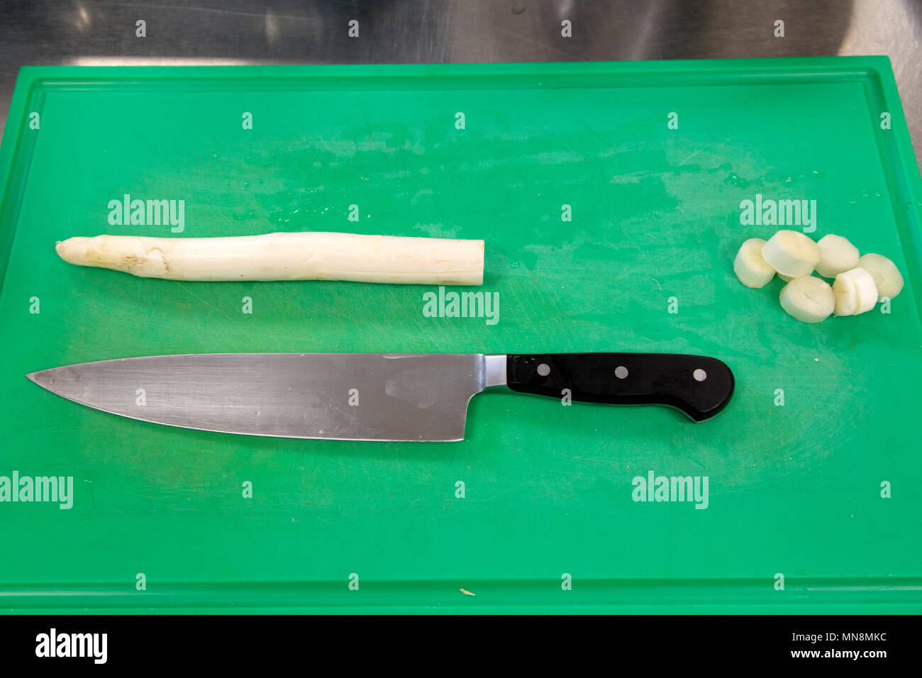 Asparagi bianchi su di un tagliere in cucina. Un coltello è anche sul tagliere. Foto Stock