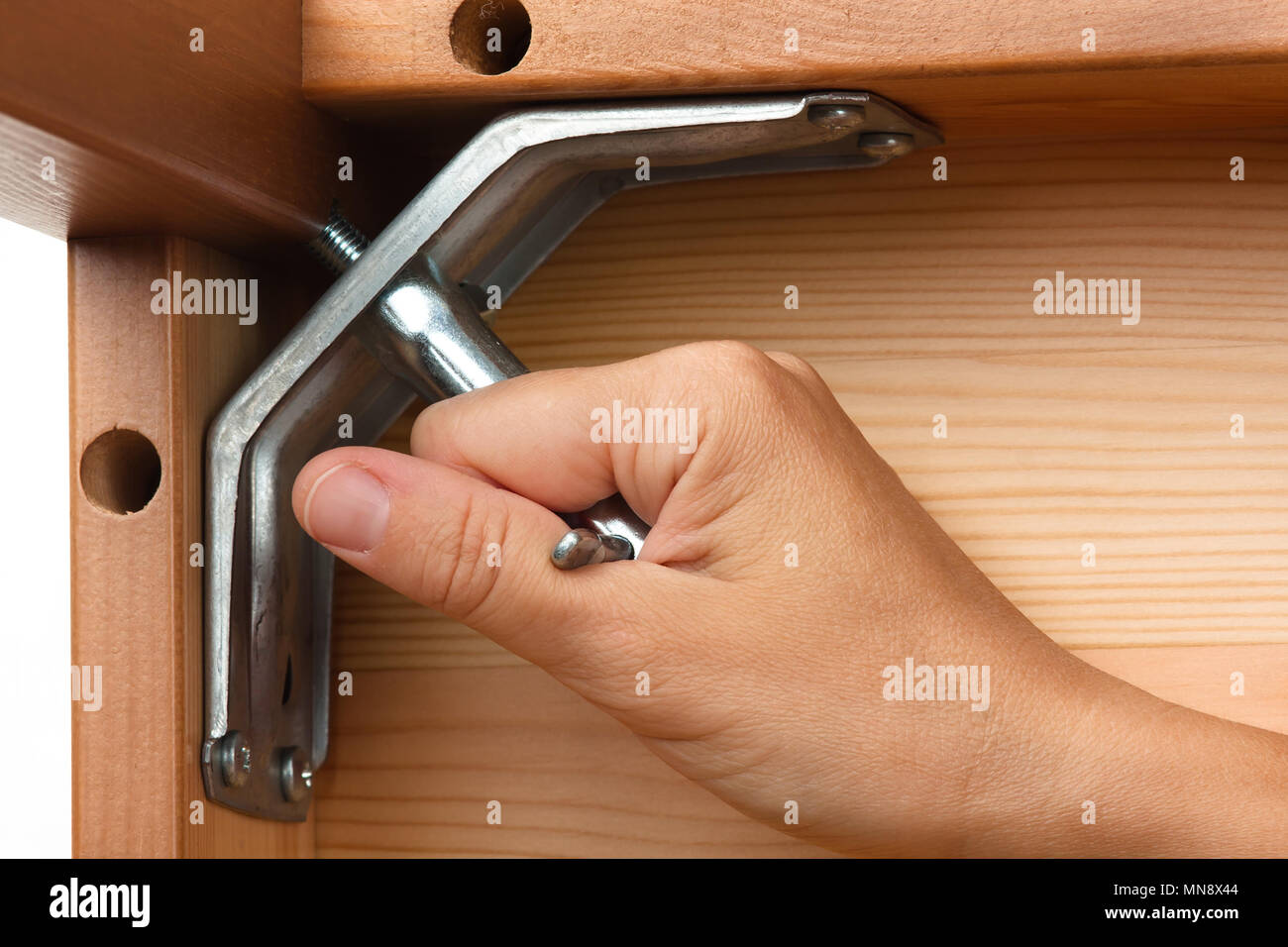 Primo piano delle mani di assemblaggio di mobili in legno con una chiave Foto Stock