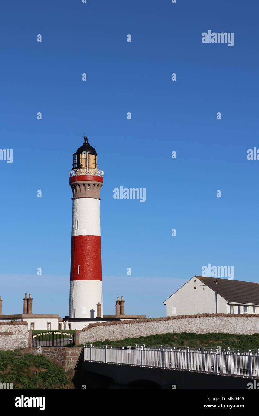 Il bianco e il rosso del faro, contro il cielo blu senza nuvole, con ringhiere in bianco sul ponte in primo piano Foto Stock