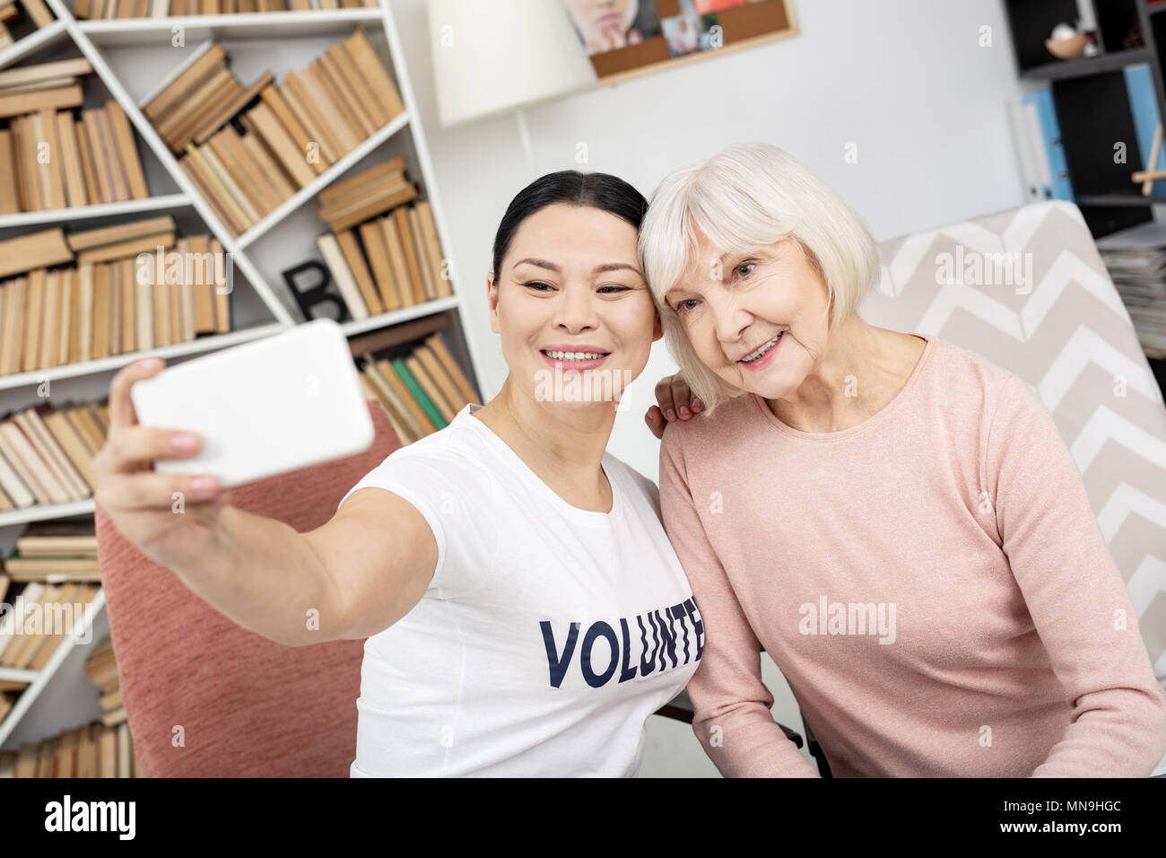 Gioioso e di volontariato senior donna prendendo selfie Foto Stock